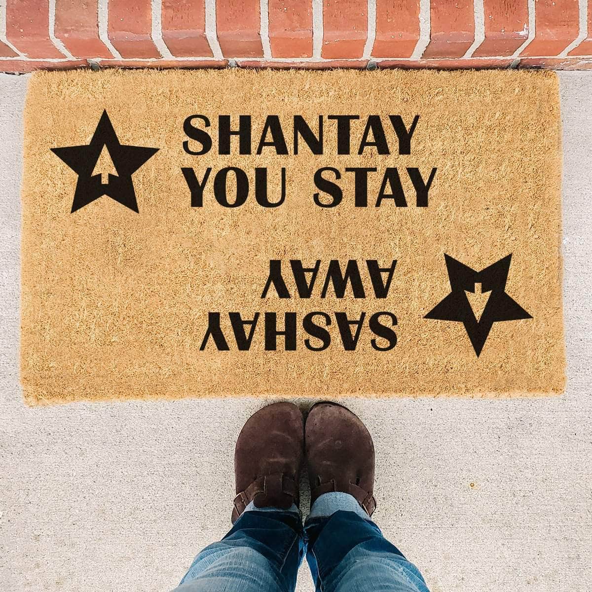 Coir doormat with two stars and a RuPaul saying 'Shantay you stay, Sashay Away' printed on in it with black ink