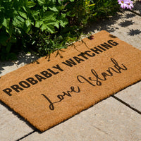 Thumbnail for Love Island doormat set beside some flowers in the sun.